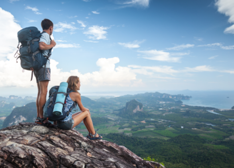 woman and man sitting on mountain staring at scenery